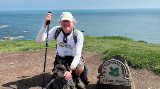 David Foster, an older caucasian man, kneeling on the grass at Lizard Point with his dog Pippin